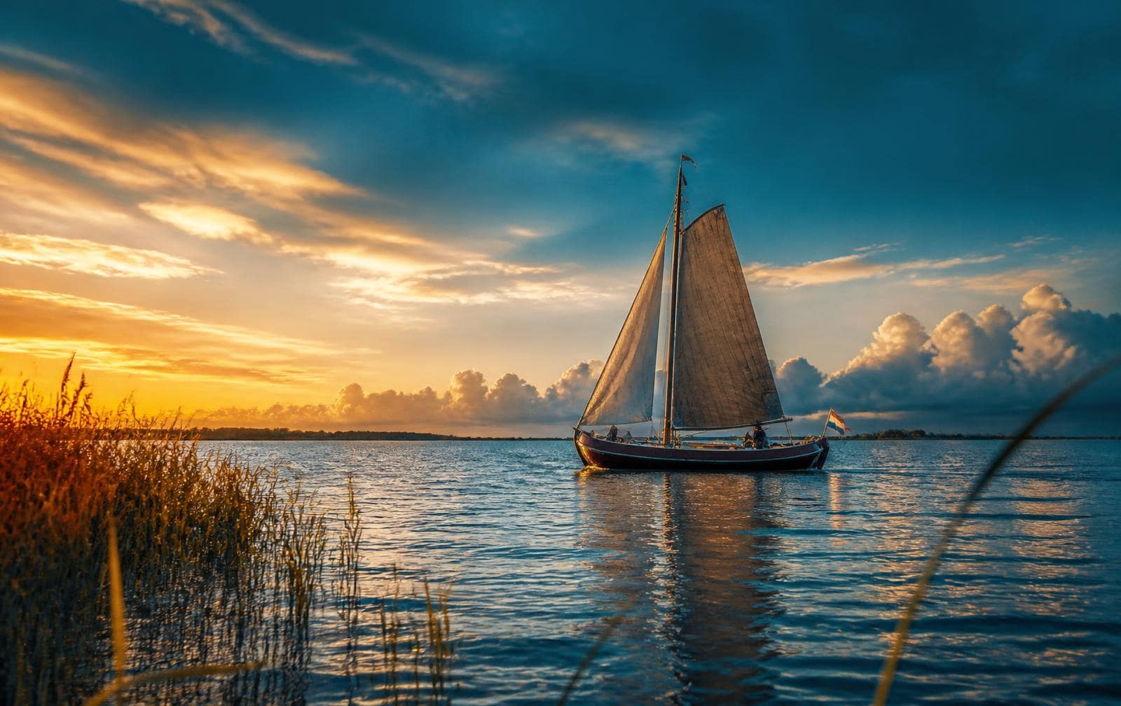 Traditioneel zeilschip op open Fries water bij gouden zonsondergang